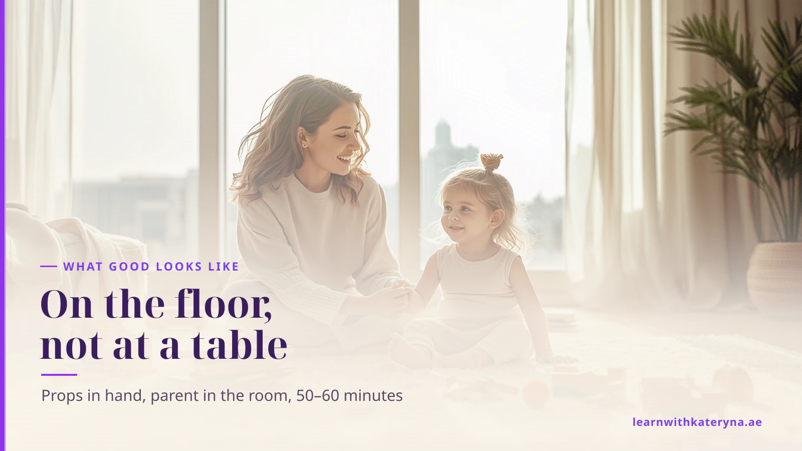 A young woman sitting on the floor at eye level with a toddler, playing together with toys in warm daylight