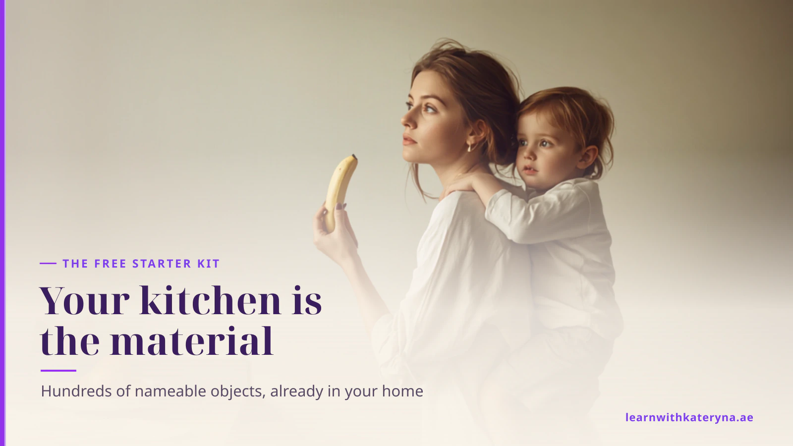 A mother holds her toddler on her hip in the kitchen and names a banana from the fruit bowl