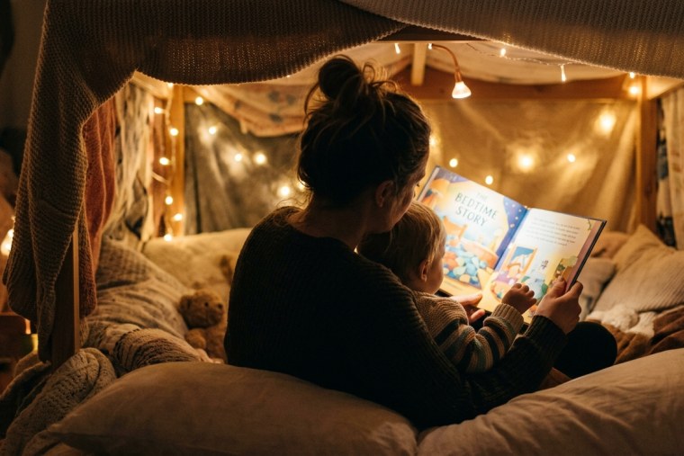 Мама і дитина читають англійську книжку під ковдрою з гірляндою — вечірній ритуал англійської вдома